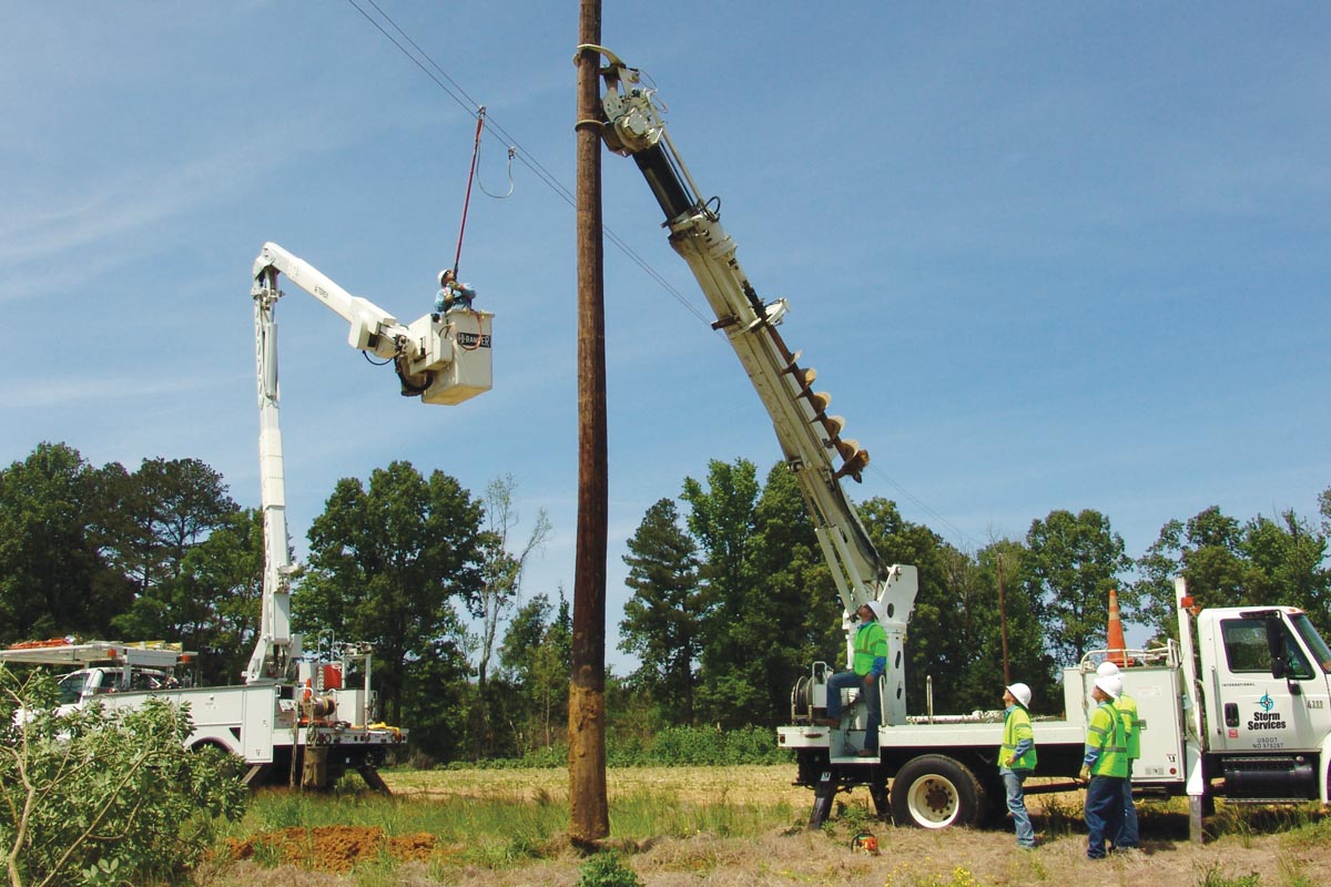 Line crews setting a replacement utility pole.